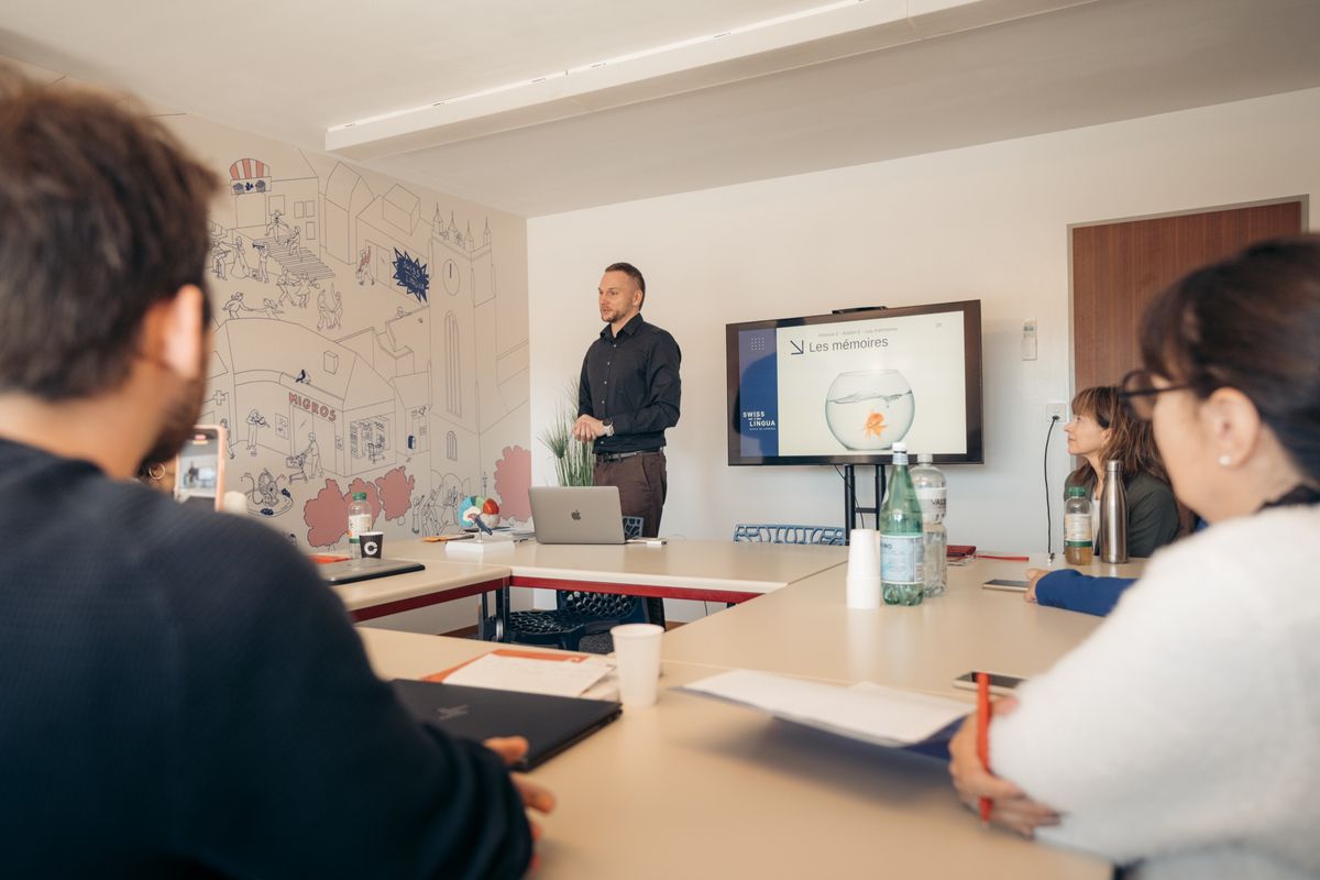 Un cours en salle, écran de présentation et participants autour de la table
